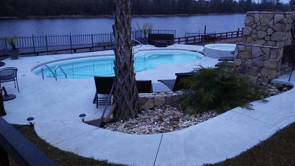 Pool beside a pond with a stone feature wall