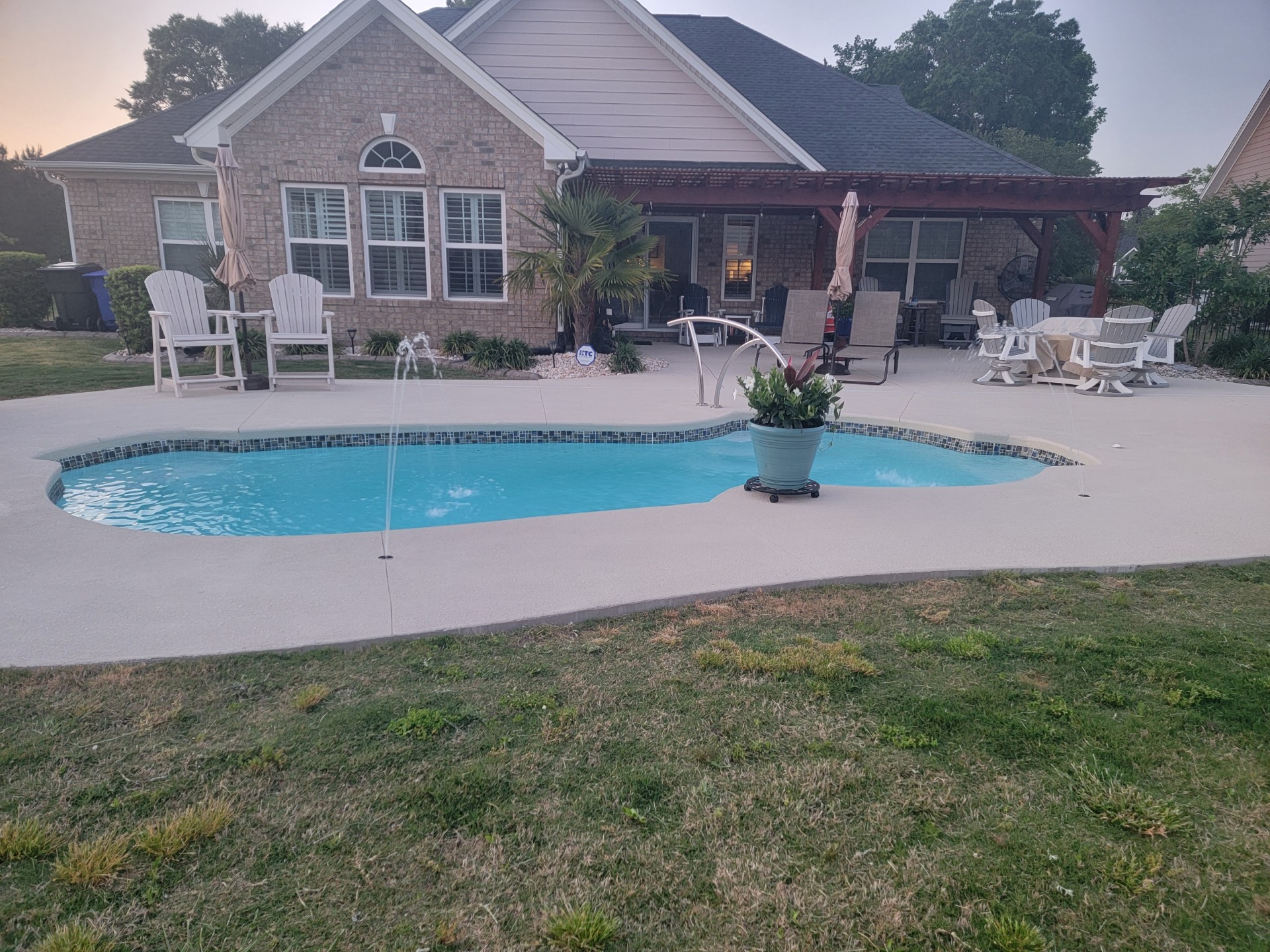 Kidney shaped pool with a patio behind a brick home