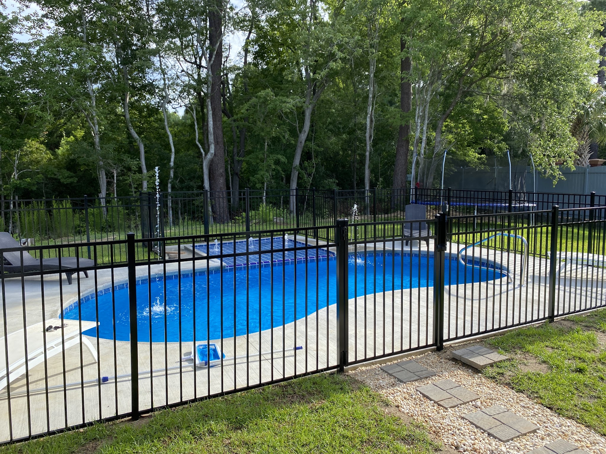 Blue pool behind a black iron fence